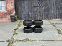 Black wheels stacked in pairs to show tire profiles and upright axle rods