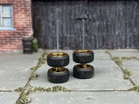 Black and gold wheels stacked in pairs to show tire profiles and upright axle rods