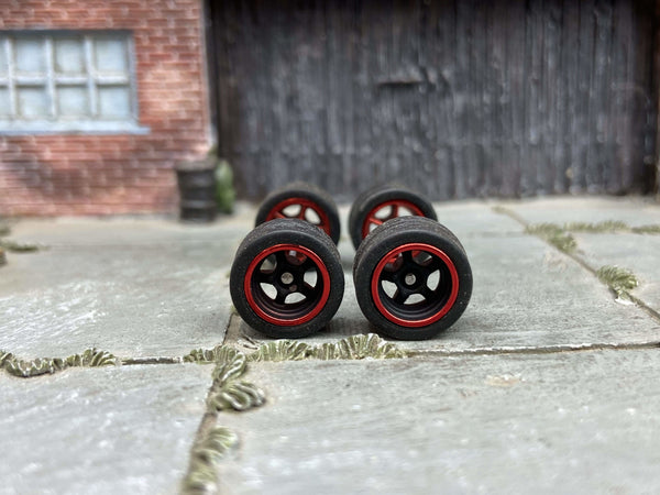 Front view of four 12mm black-and-red racing 5-spoke wheels with black rubber tires