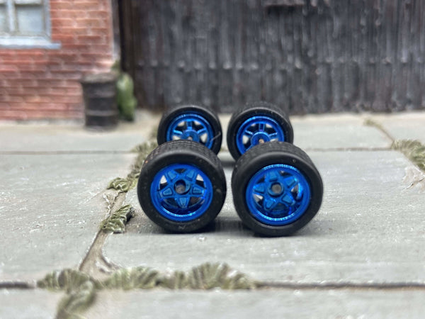 Front view of four 10mm blue anodized 5-star wheels with black rubber tires