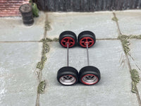 Overhead view of chrome and red 4-spoke wheels with black rubber tires positioned on axle rods