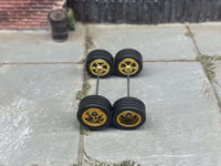 Overhead view of four gold 5-star wheels with black rubber tires positioned on axle rods