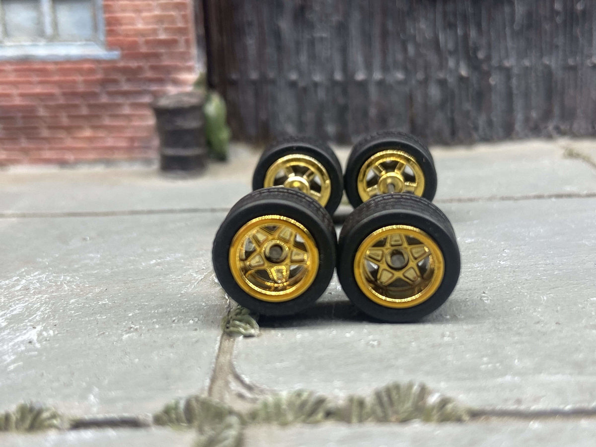 Front view of four 10mm gold 5-star wheels with black rubber tires
