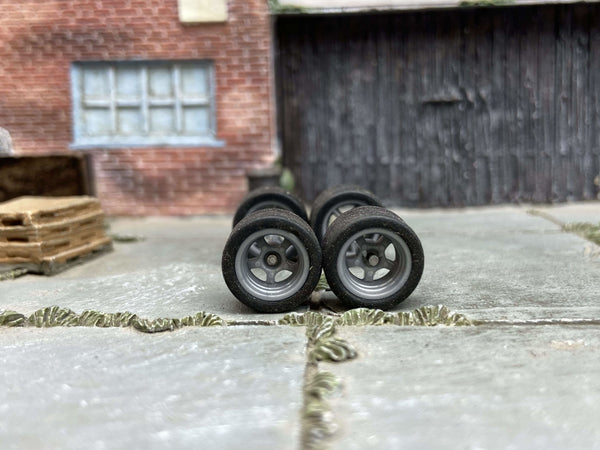 Front view of four 12mm gray racing 5-spoke wheels with black rubber tires