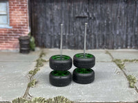 Green wheels stacked in pairs to show tire profiles and upright axle rods