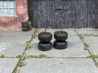 Green/drab wheels stacked in pairs to show tire profiles and upright axle rods