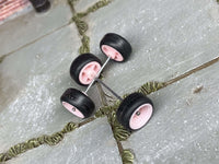 Overhead view of pink wheels showing front faces, rear hubs, and two crossing axle rods