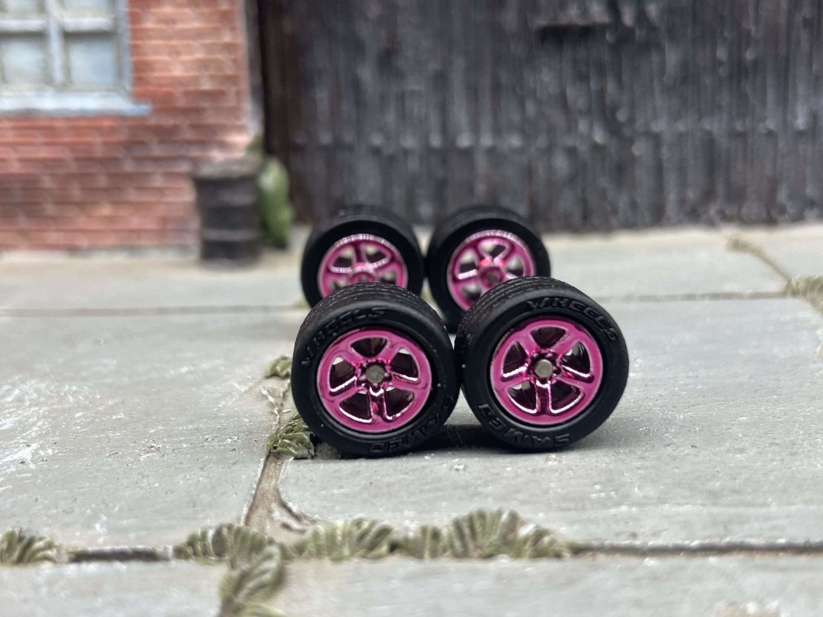 Front view of four 10mm pink anodized 5-star wheels with black rubber tires