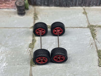 Overhead view of four red anodized 5-star wheels with black rubber tires positioned on axle rods