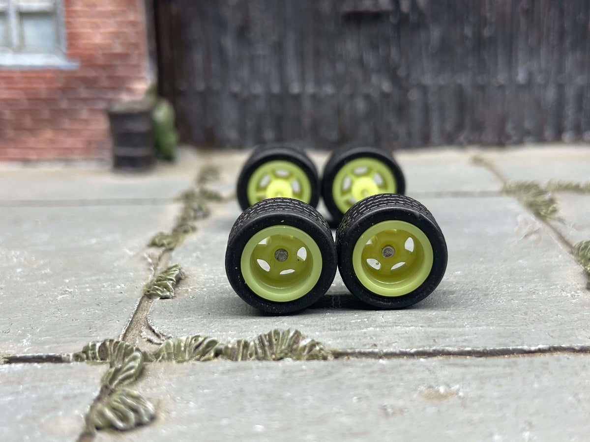 Front view of four 10mm yellow-green 3-spoke wheels with black rubber tires