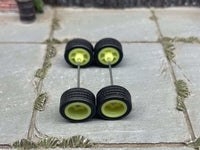 Overhead view of yellow-green 3-spoke wheels with black rubber tires positioned on axle rods
